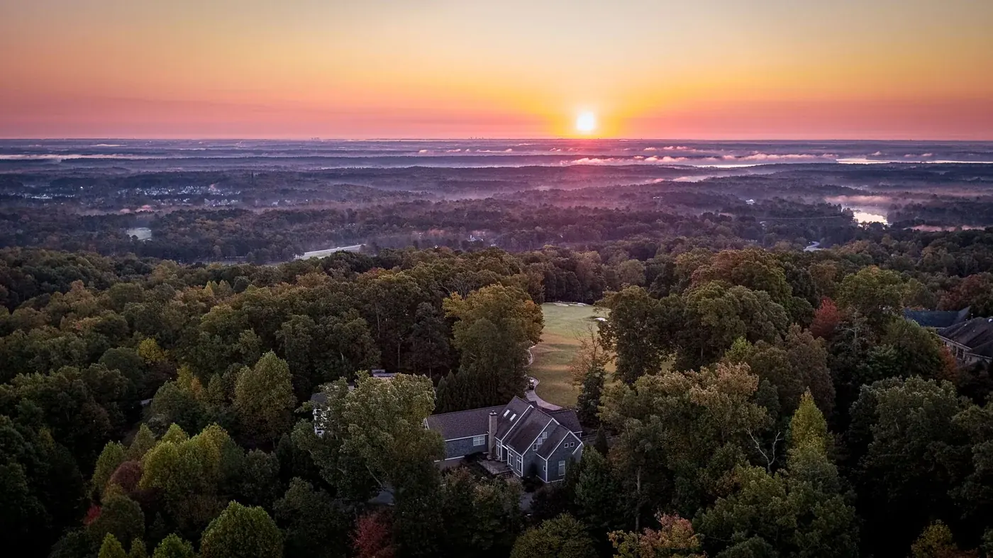 Wooded residential community at sunrise, seen from above
