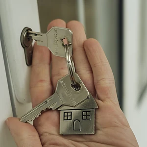 Hand holding house keys by a front door